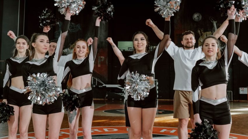 Energetic cheerleading team performing indoors with pompoms and uniforms.